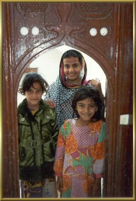 Kinder im Eingang zu ihrem Haus in Sur